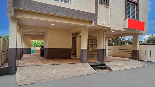 A building with a covered entrance area, a gated driveway, and a visible door leading into the building. - Fabhotel Seven Elite (Paud)