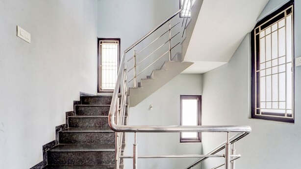 Eine Treppe mit Metallgeländern und Handlauf, die zu einer oberen Etage führt.
