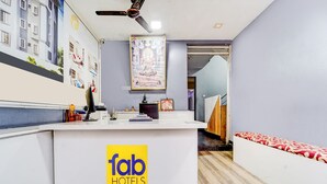 Ein Hotel-Empfangsbereich mit einer weißen Theke, einem Deckenventilator und einem Wandbild.