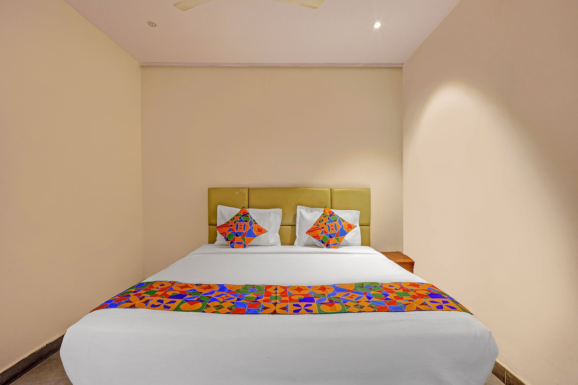 A hotel room with a bed, two pillows, a headboard, and a ceiling fan.