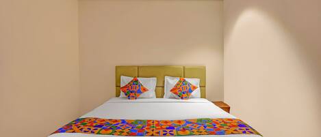 A hotel room with a bed, two pillows, a headboard, and a ceiling fan.