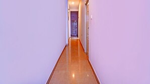 A long, narrow hallway with a polished wooden floor and light purple walls.