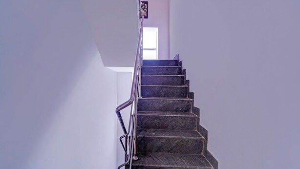 A staircase with a metal railing leading to a room with a window.
