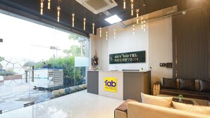 A hotel reception area with a modern design, featuring a reception desk, a sofa, and a sign indicating the reception. - Fabhotel Sky I (Gurugram)