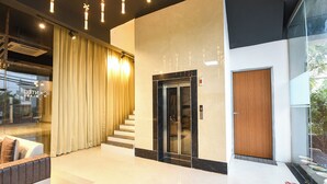 A modern lobby with a glass entrance, a wooden door, and a staircase leading to an elevator. - Fabhotel Sky I (Gurugram)