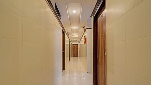 A long, narrow hallway with tiled walls and a shiny floor, leading to a wooden door at the end. - Fabhotel Sapthagiri Suites Inn (Bengaluru)