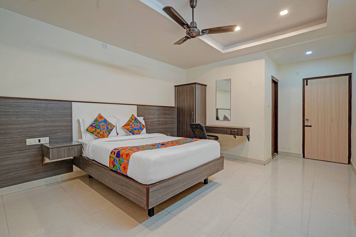 A modern bedroom with a large bed, a ceiling fan, a wardrobe, and a mirror.