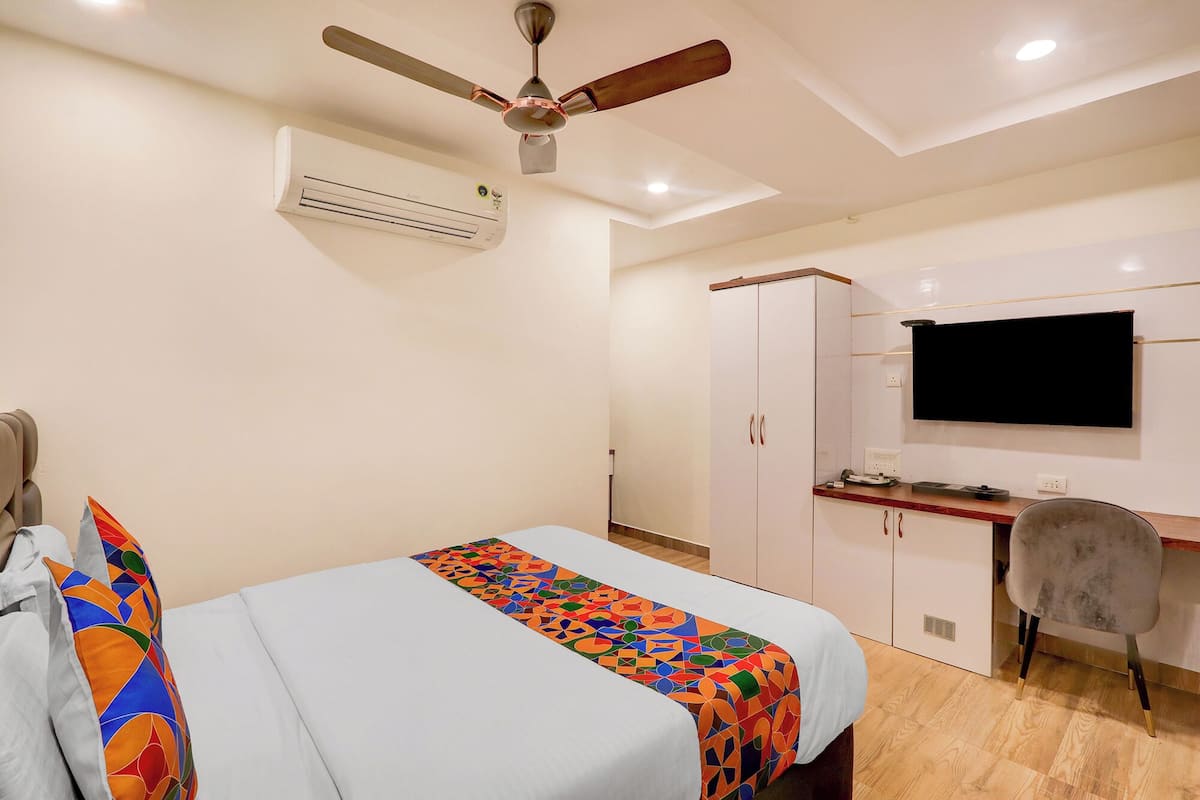 Ein Schlafzimmer mit Bett, Schreibtisch, Sessel, Fernseher und Deckenventilator.