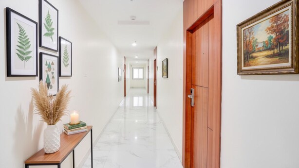 A hallway with framed botanical prints, a vase with pampas grass, and a lit candle on a console table. - Fabhotel Radha Rani Residency (Khammam)