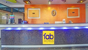 A hotel reception desk with a modern design, featuring a prominent logo and a digital screen displaying information. - Fabhotel Amutham Residency (Kanyakumari)