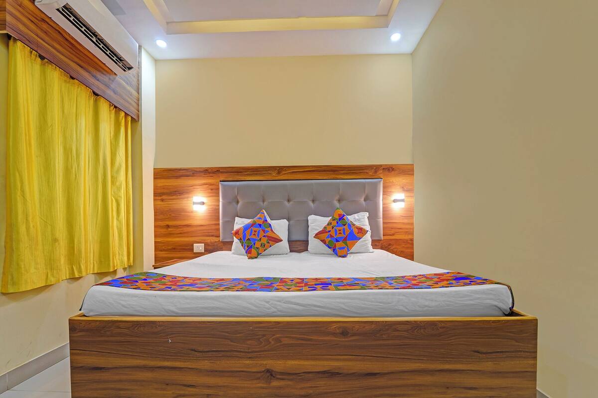 A bedroom with a wooden headboard, a bed with white bedding, and a colorful geometric-patterned throw.