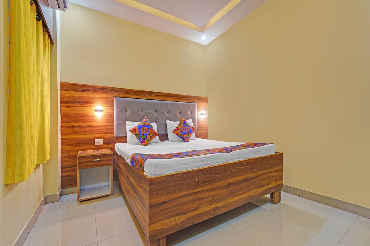 A modern bedroom with a wooden headboard, a small bedside table, and a bed with patterned bedding.