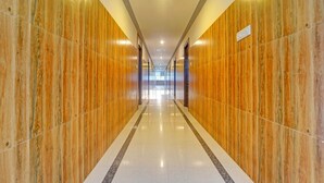A long, narrow hallway with polished wooden walls and a shiny tiled floor. - Fabhotel Amutham Residency (Kanyakumari)