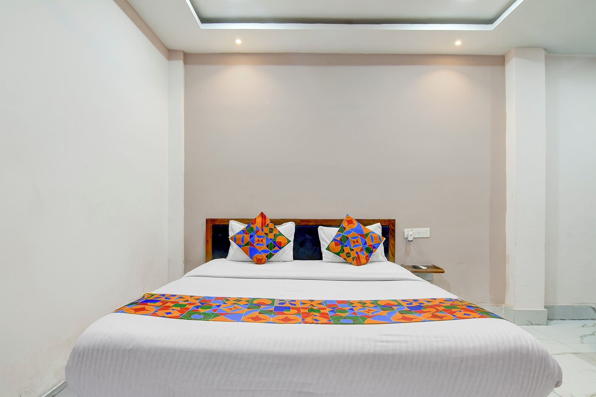 Una habitación de hotel moderna con una cama grande, un cabecero y una lámpara en el techo.