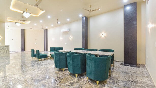 Une salle de conférence spacieuse, dotée d’un sol en marbre, de chaises recouvertes d’un tissu vert et d’une longue table.