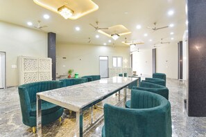 A spacious conference room with a marble table, teal upholstered chairs, ceiling fans, and recessed lighting. - FabHotel The Fort - Near Amber Palace (Jaipur)