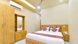 Une chambre d’hôtel moderne dotée d’un grand lit, d’une armoire en bois et d’un système de climatisation intégré.