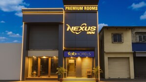 A hotel with "Premium Rooms" and "Nexus Inn" signage, a "fabHOTELS" sign, and a modern facade with large windows and potted plants. - Fabhotel Nexus Inn (Mumbai)