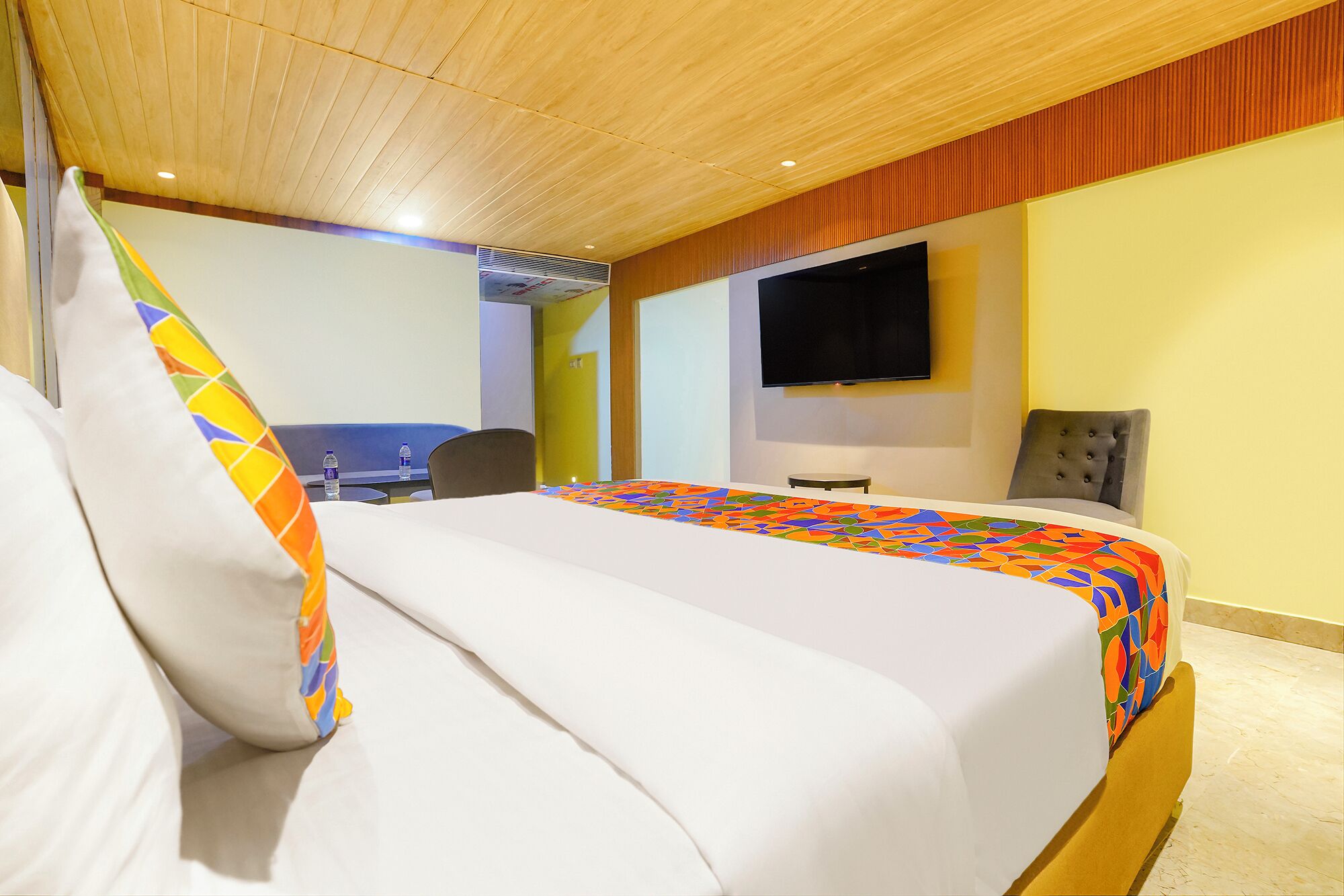 Ett hotellrum med en säng, ett skrivbord, en stol, en tv och ett fönster.
