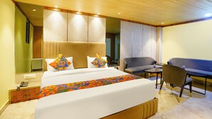A hotel room with a large bed, a sofa, a small table, and a chair. - Fabhotel Nexus Inn (Mumbai)