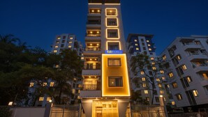 Um hotel com vários andares, exibindo uma placa grande da marca 'fabHOTELS', com fachada moderna, janelas iluminadas e entrada por portão.