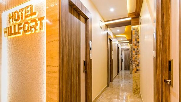 A hotel hallway with a sign reading "HOTEL HILFIGER" and doors leading to rooms. - Fabhotel Hill Fort (Kolkata)