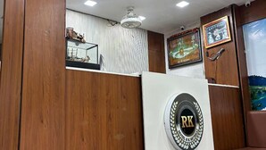A reception area with a wooden reception desk, a ceiling fan, and framed artwork on the walls. - Fabhotel Rk Retreat (Bhopal)