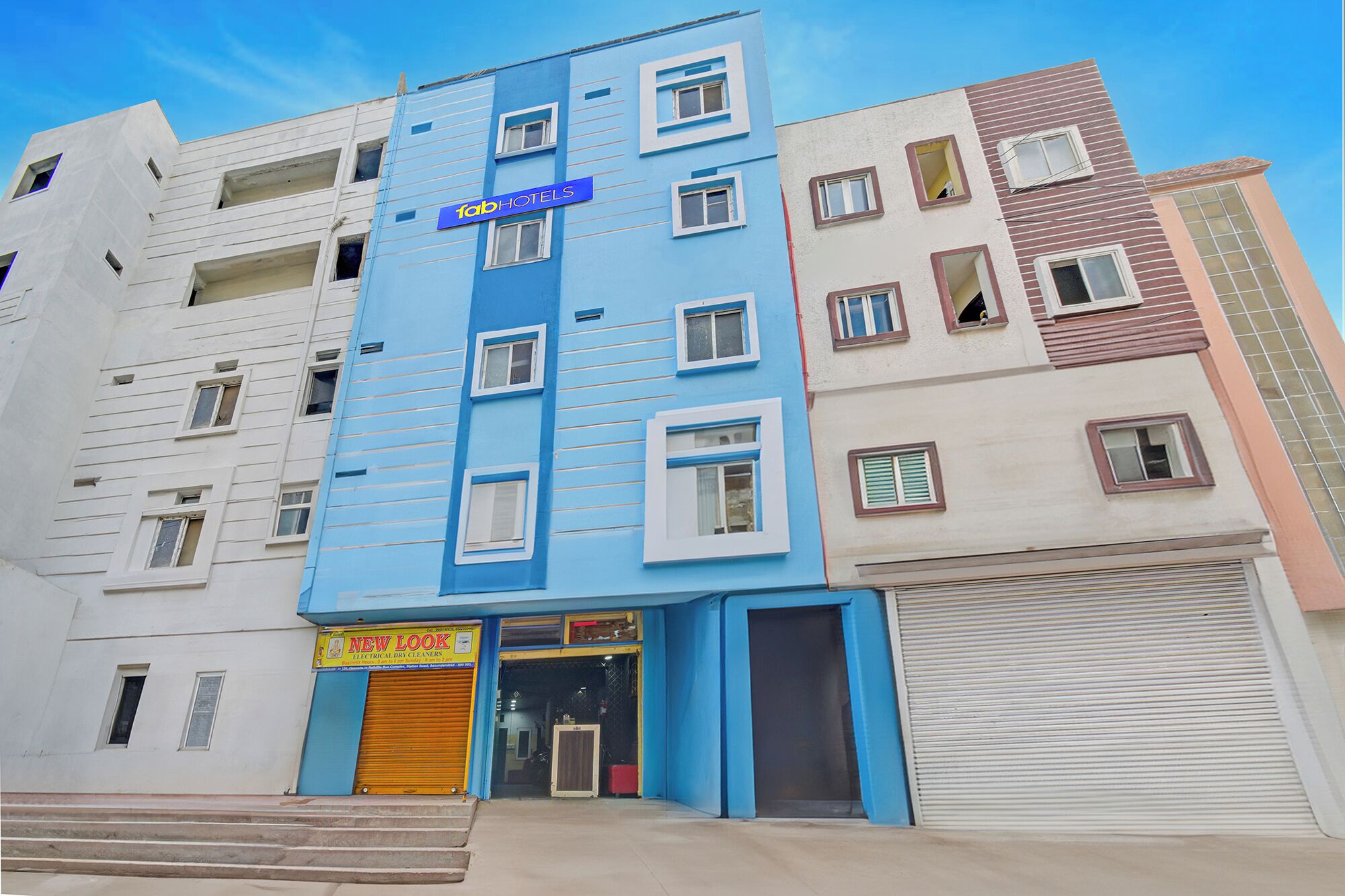 A multi-story building with a blue facade and a sign for 'Fab Hotels'.