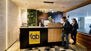 A reception desk at Fab Hotels with a modern design, including a check-in counter, a wooden reception area, and a green wall with plants. - Fabhotel Casa Grand (Hyderabad)