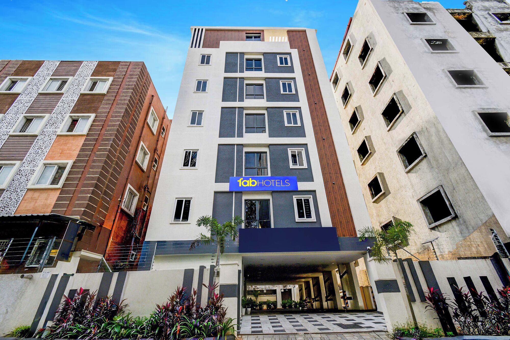 A multi-story hotel with a modern facade, a prominent 'fabHOTELS' sign, and a well-maintained entrance area with potted plants.