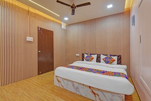 A bedroom with a bed, wooden panel walls, a ceiling fan, and a wooden floor. - Fabhotel The Heaven (Pune)