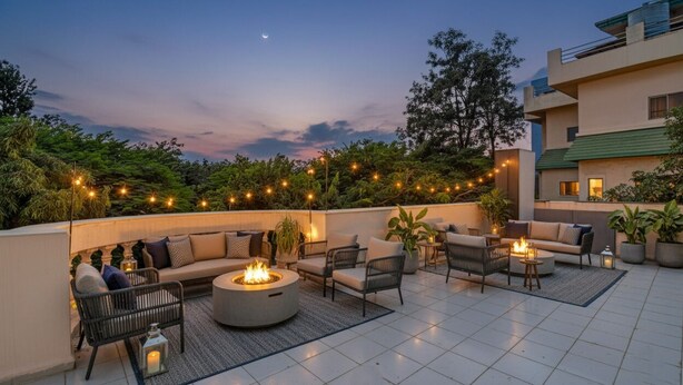 An outdoor patio area with seating, a fire pit, and string lights. - Fabhotel The Heaven (Pune)