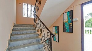 A staircase with a metal railing, a window with bars, and two framed artworks on the wall. - Fabhotel The Heaven (Pune)