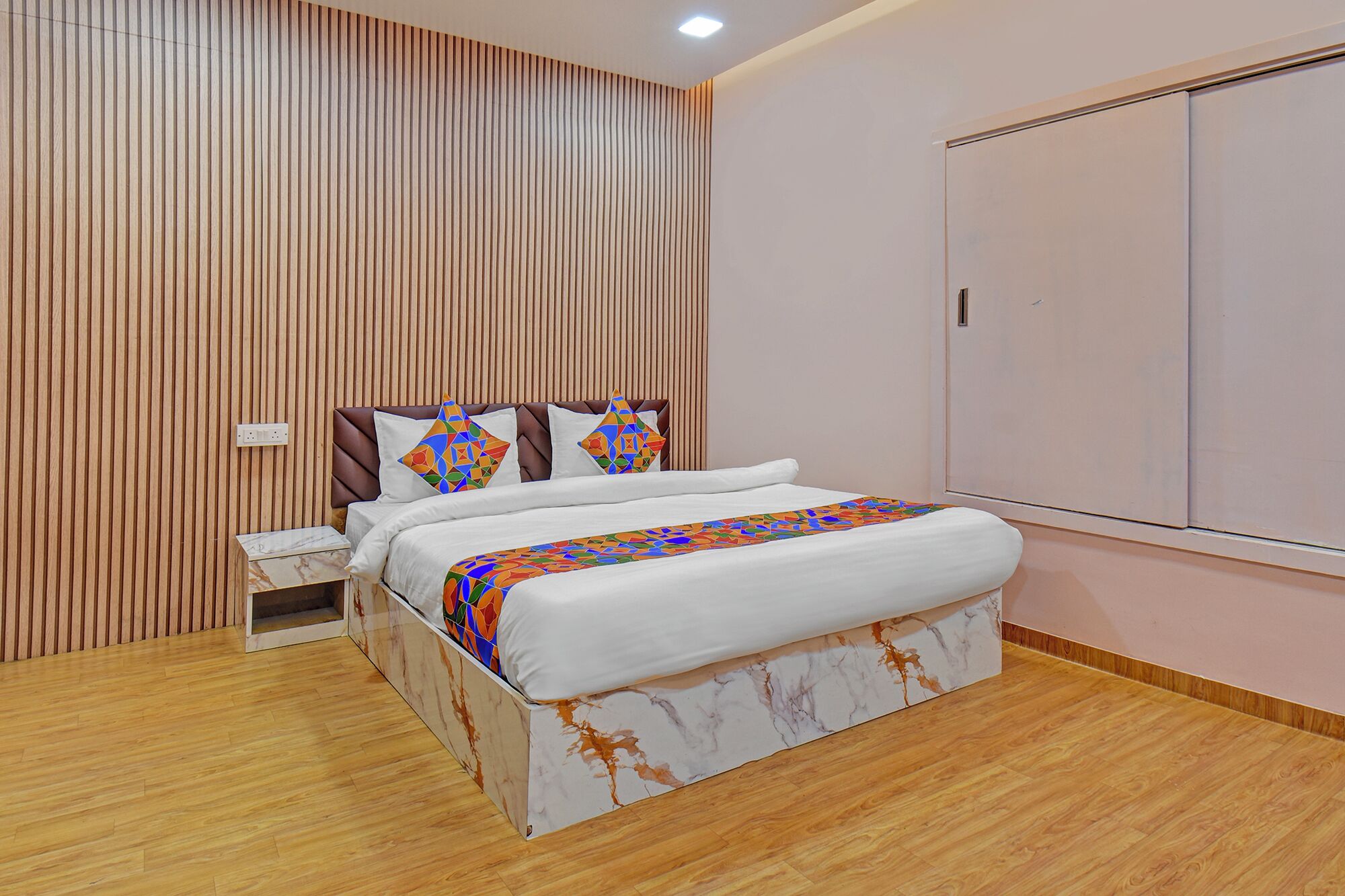 Une chambre à coucher moderne avec un lit, un mur recouvert de lambris en bois, une table de chevet et une armoire.