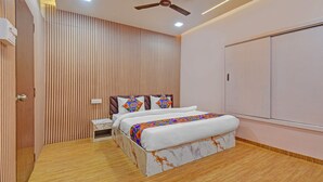 A bedroom with a bed, a wardrobe, a ceiling fan, and a nightstand. - Fabhotel The Heaven (Pune)