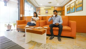 A reception area with orange seating, a coffee table, and framed artwork on the wall. - Fabhotel Ratna Mahal (Mumbai)