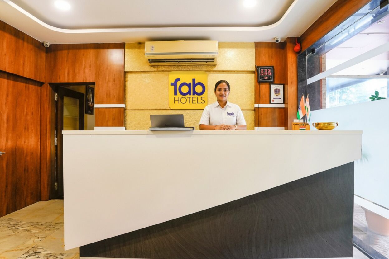 Una recepción con un cartel que dice "fab hotels", una computadora portátil y una bandera.
