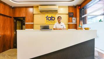 Una recepción con un cartel que dice "fab hotels", una computadora portátil y una bandera.