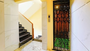 A staircase with marble walls and a black railing, leading to a door with a metal gate. - Fabhotel Ratna Mahal (Mumbai)