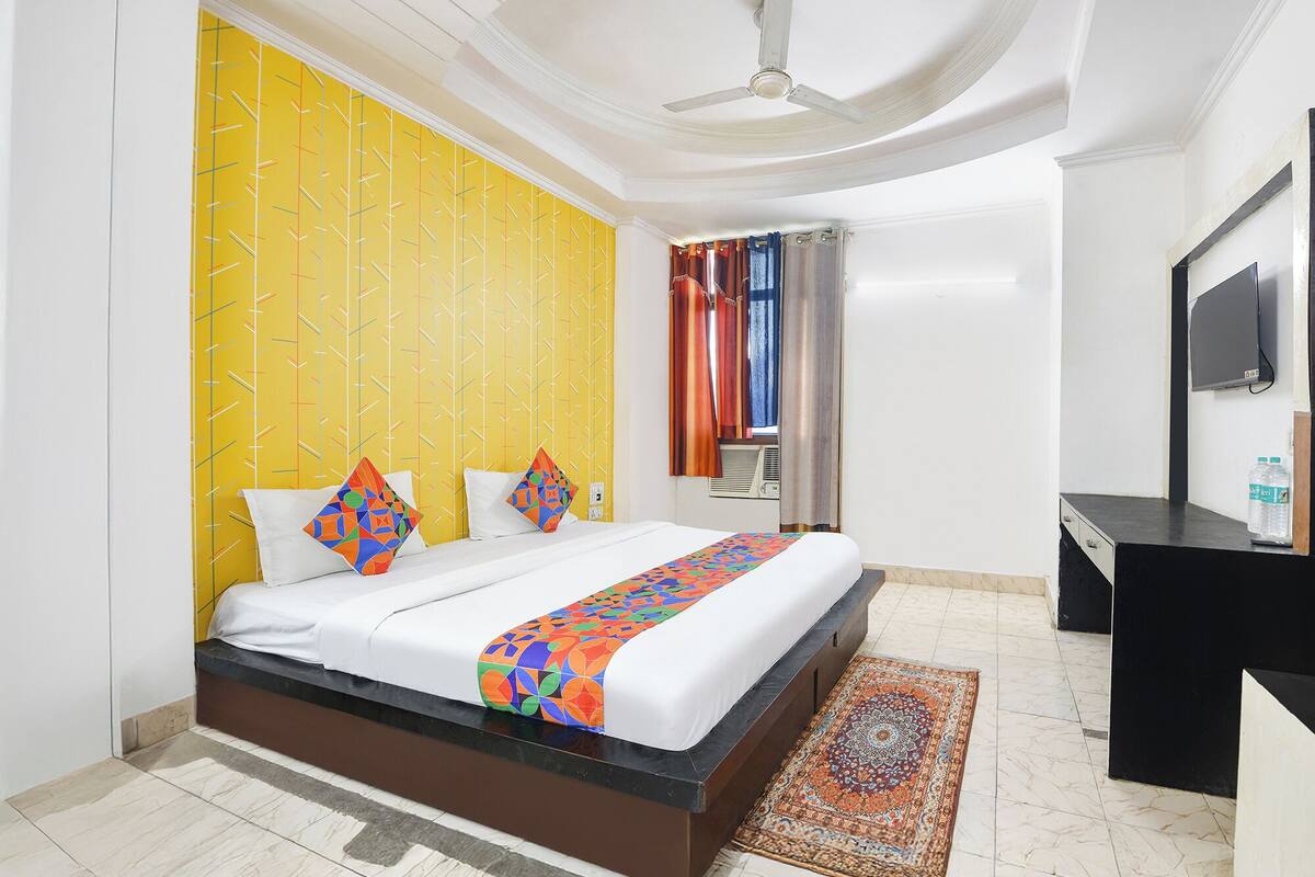 A hotel room with a bed, a desk, a television, and a window with curtains.