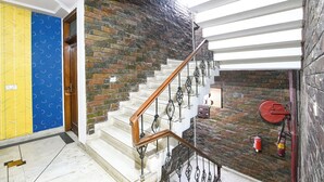 Una escalera con barandilla de madera y barandales de metal, que lleva a un rellano con un extintor de incendios fijado en la pared.