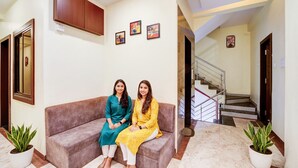 A lobby with a sofa, potted plants, framed pictures on the wall, and a staircase. - Fabhotel The Shloka (Bhopal)