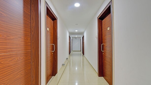 A hallway with wooden doors on both sides and a tiled floor. - Fabhotel Sri Sai (Pune)