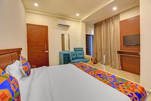 A hotel room with a bed, a chair, a TV, and a window with curtains. - Fabhotel Sri Sai (Pune)