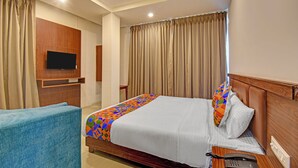 A hotel room with a bed, a TV mounted on the wall, a telephone, and a chair. - Fabhotel Sri Sai (Pune)