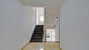 A hallway with a staircase leading to a door. - Fabhotel Sri Sai (Pune)