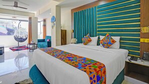 A hotel room with a large bed, a hanging chair, a desk, and a view of the outside. - Fabhotel Small Daddy Plus (Calangute)