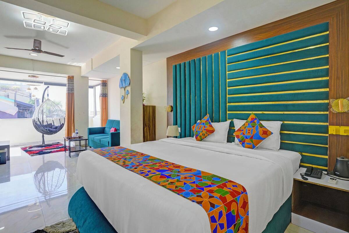 A hotel room with a large bed, a hanging chair, a desk, and a view of the outside.