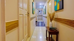 A hallway with doors, a wooden console table with a vase and books, and framed artwork on the walls. - Fabhotel 4 Pillar's - Nr Big Daddy Casino, Panaji (Panaji)