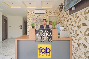 Un comptoir d’accueil d’hôtel avec une enseigne indiquant « HÔTEL AURIKA RETREAT » et un logo pour « fab HOTELS ».